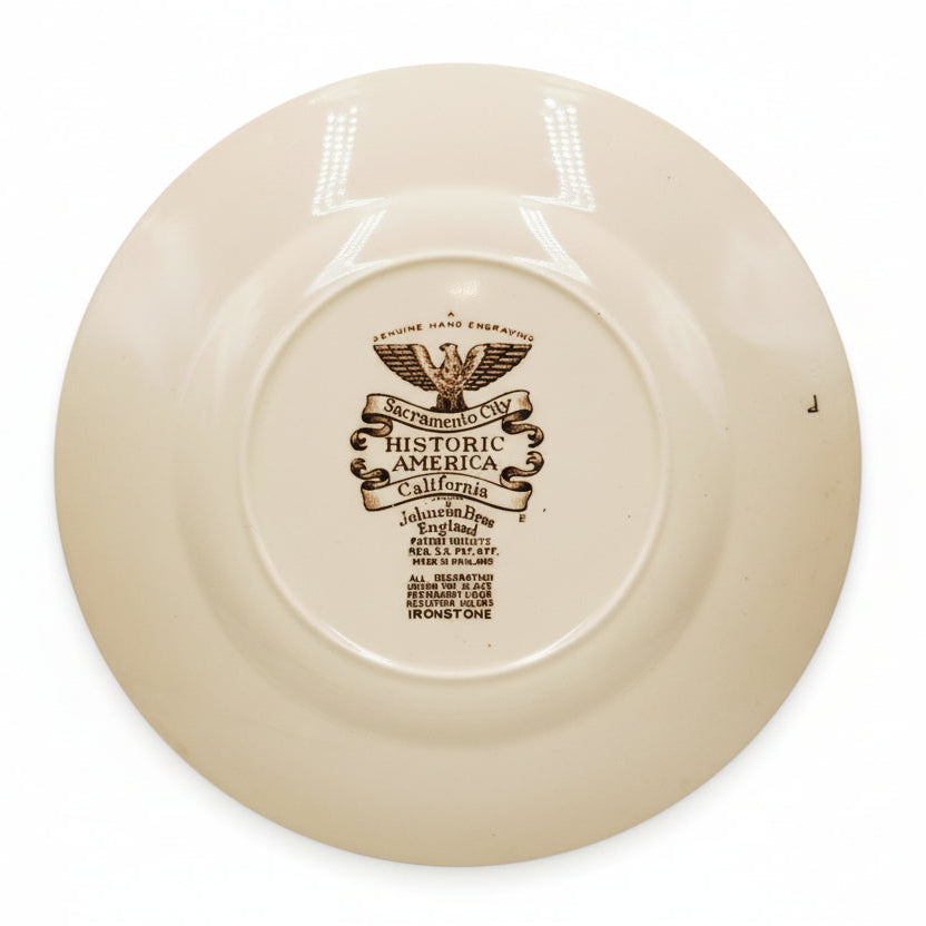 Beige ceramic plate with a decorative emblem and text on a white background