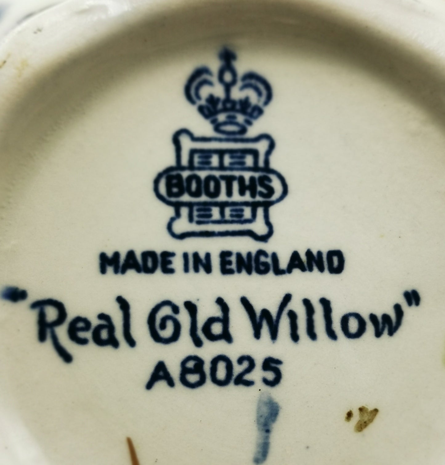 Close-up of the underside of a white porcelain item printed with a blue crest, the word 'BOOTHES', 'MADE IN ENGLAND', and 'Real Old Willow A8025'.