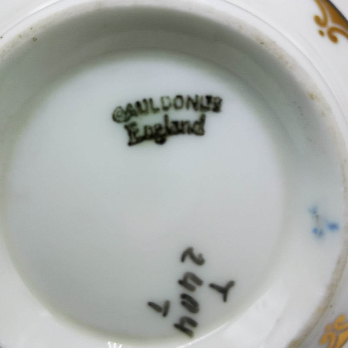 Close-up of the inside bottom of a white porcelain bowl or cup, showing a dark printed mark reading 'Aldworth England' and handwritten markings near the lower edge.