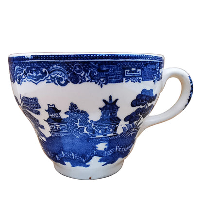 A white ceramic teacup with a blue traditional landscape pattern featuring pagodas, trees, and water, shown against a plain white background.