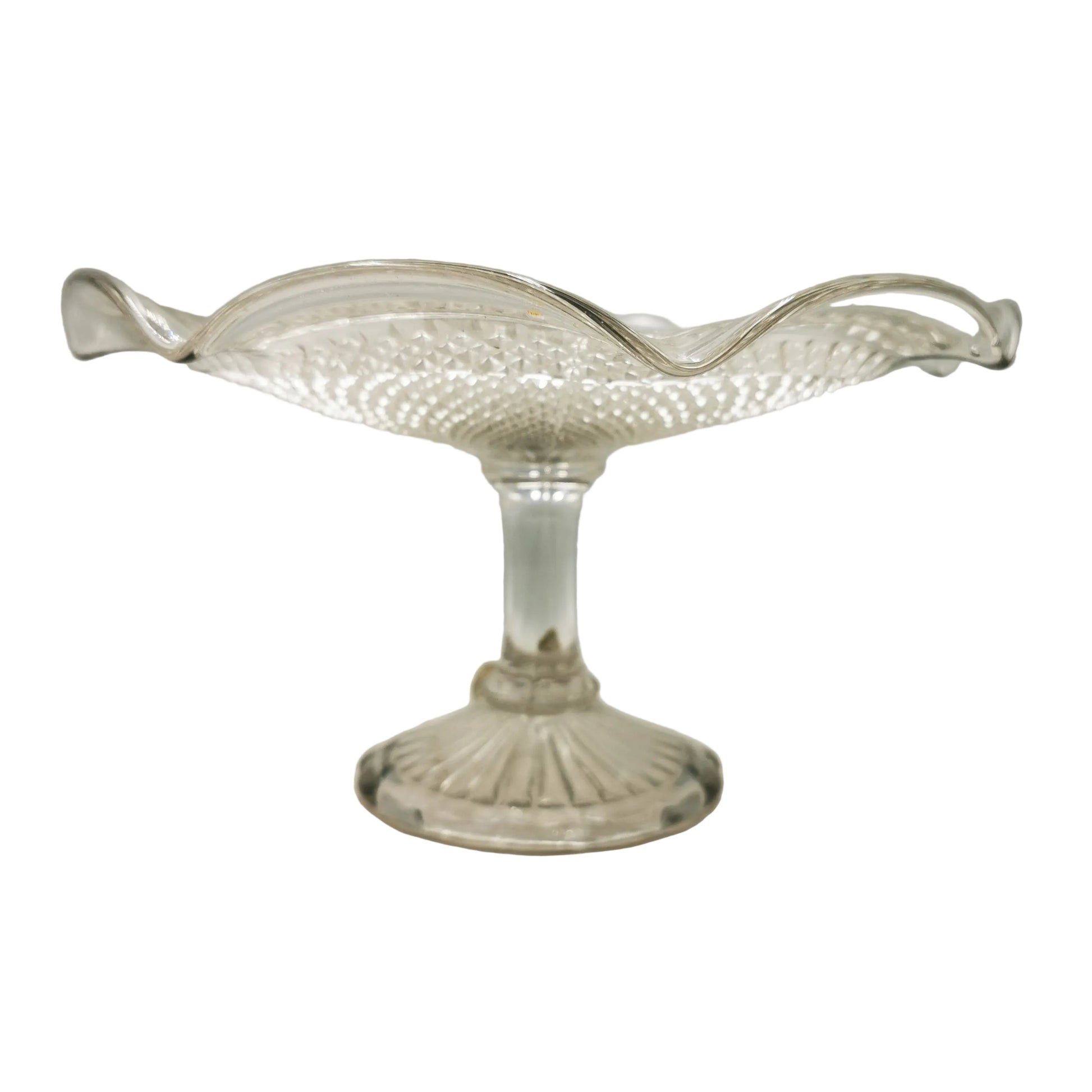 A clear glass pedestal bowl with a textured, diamond-cut pattern and wavy rim, set against a neutral light gray background.