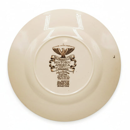 Beige ceramic plate with a decorative emblem and text on a white background