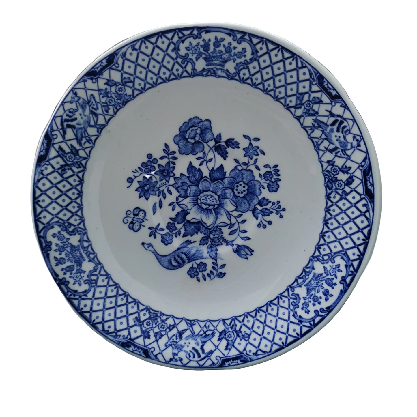 Blue and white floral patterned plate on a wooden surface with greenery in the background