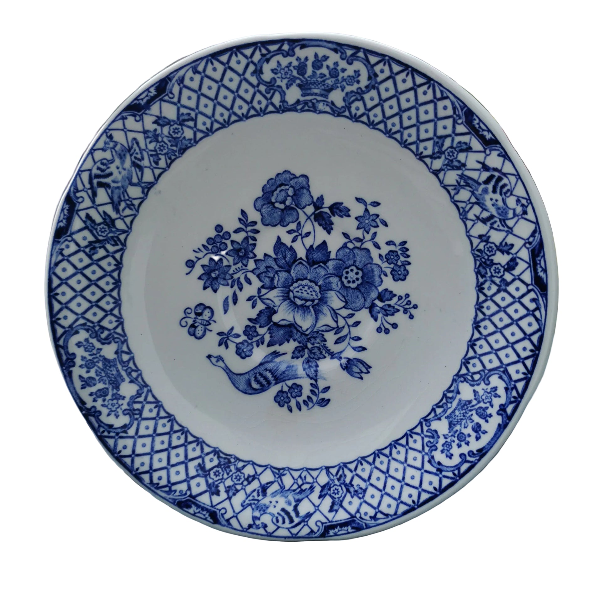 Blue and white floral patterned plate on a wooden surface with greenery in the background