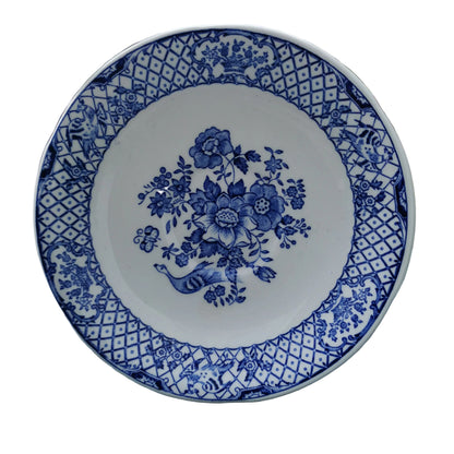 Blue and white floral patterned plate on a wooden surface with greenery in the background