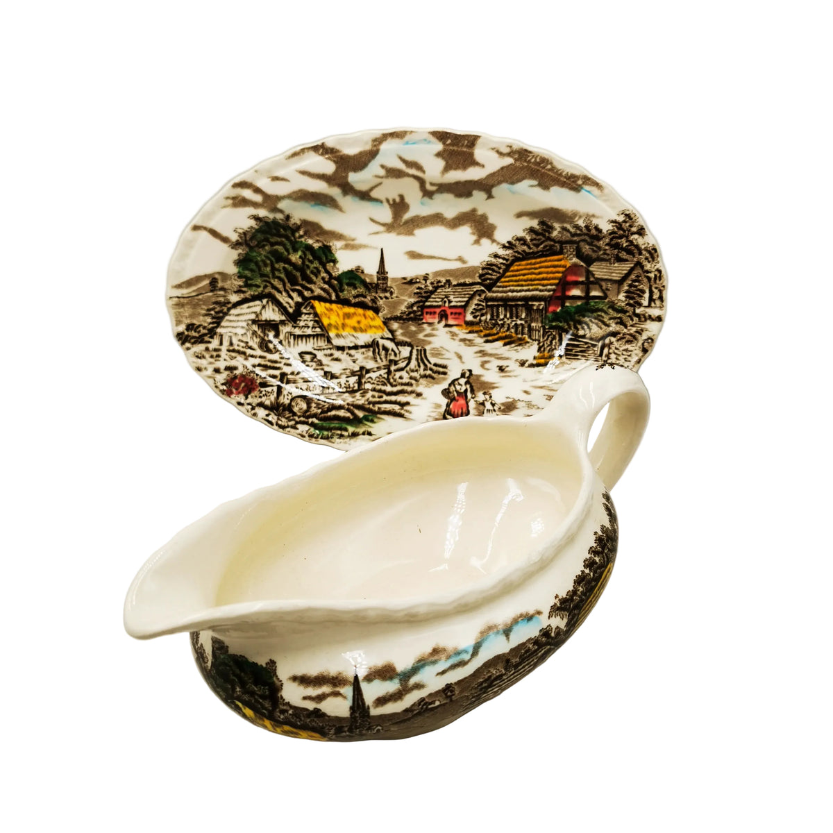 A ceramic gravy boat and matching oval platter with hand-painted country landscape scenes in brown, cream, green, and yellow tones, photographed on a plain light background.