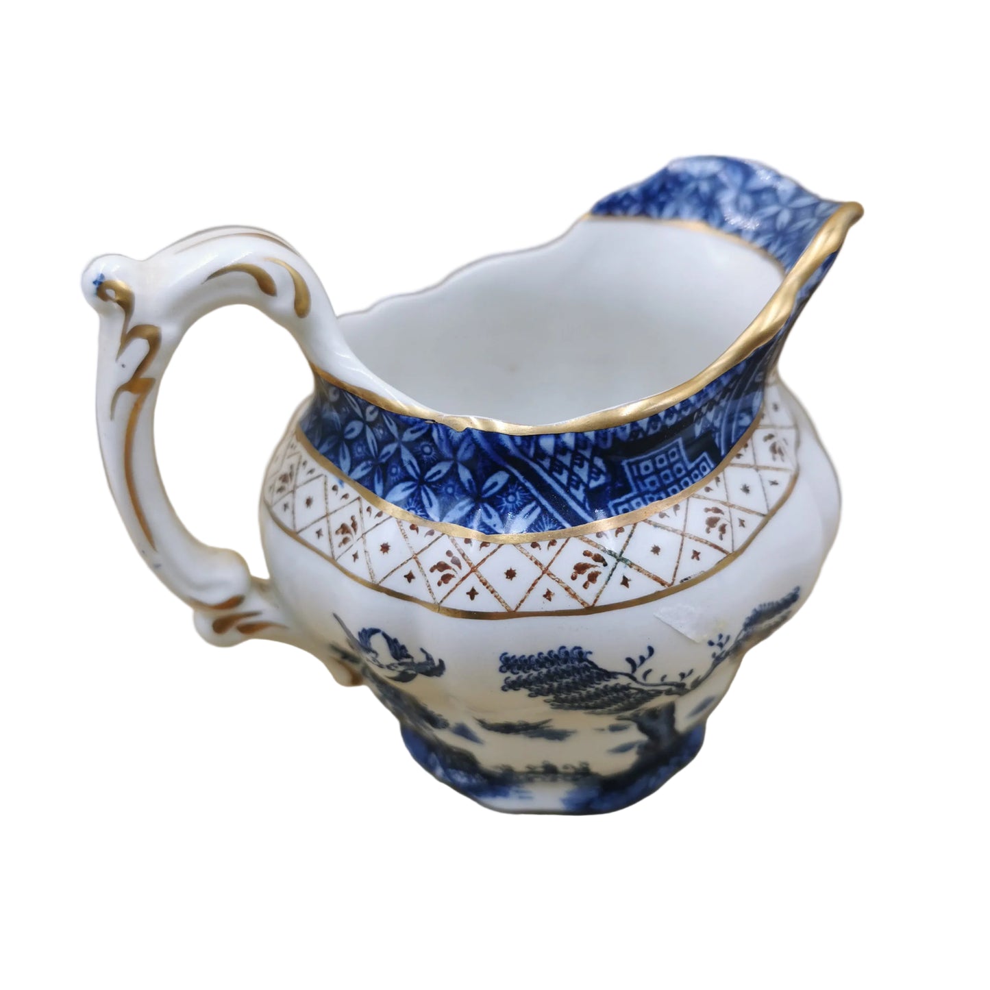 A white booth creamer pitcher decorated with blue floral patterns, gold trim, and a blue-and-white geometric border, photographed against a tan cardboard background. Real Old Willow 