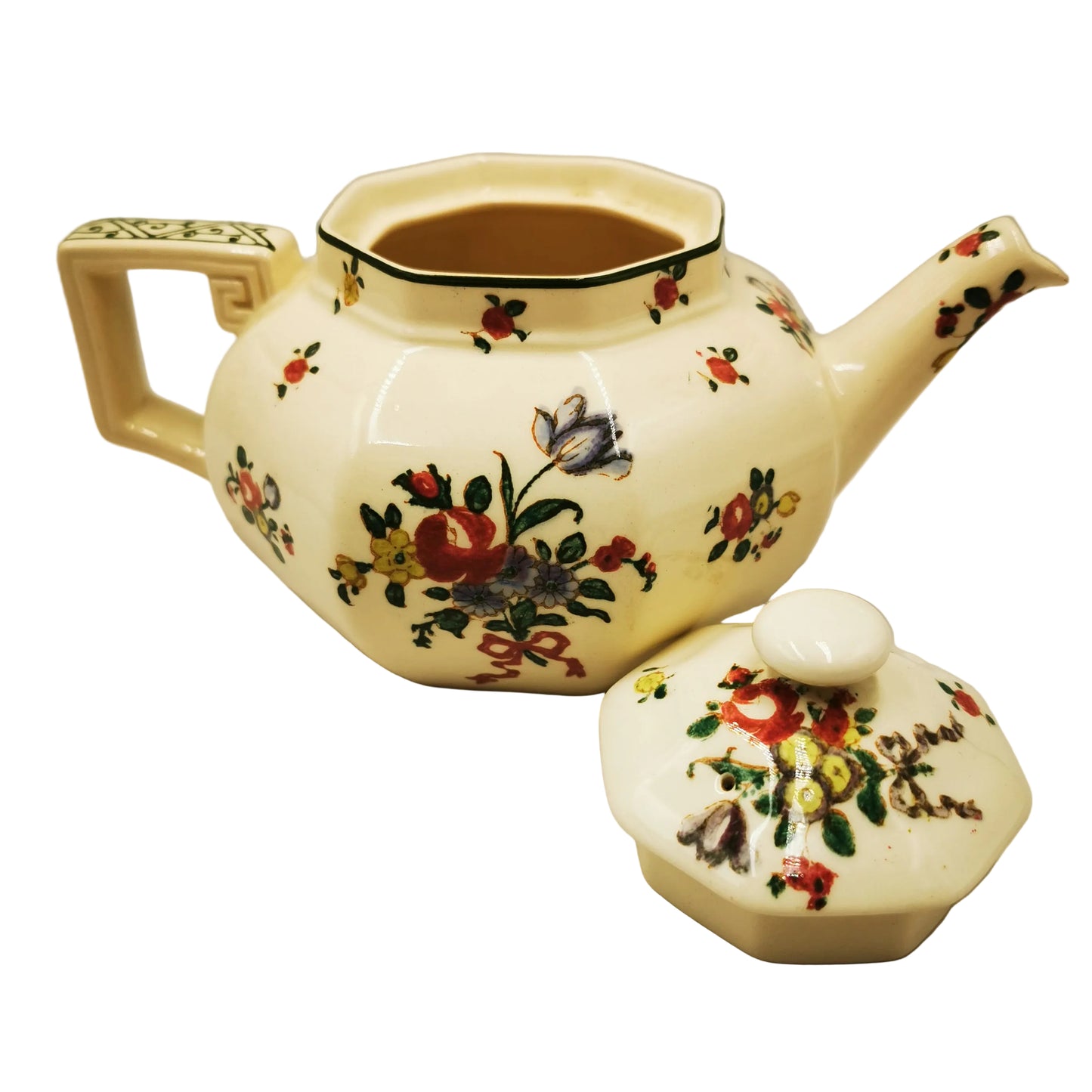 An antique ceramic teapot with a matching lid, decorated with a hand-painted floral pattern on a cream-colored glaze, set against a plain light background.