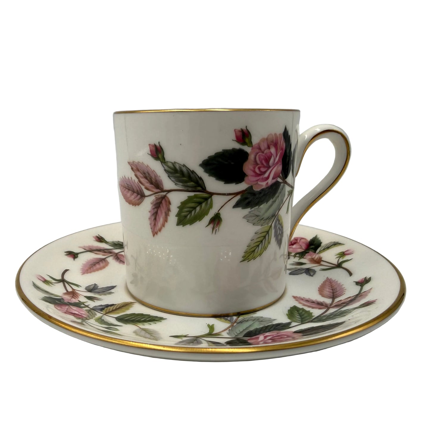 A white porcelain teacup and saucer set decorated with a pink rose and green leaf floral pattern, accented with gold trim on the rim and edge of the saucer.
