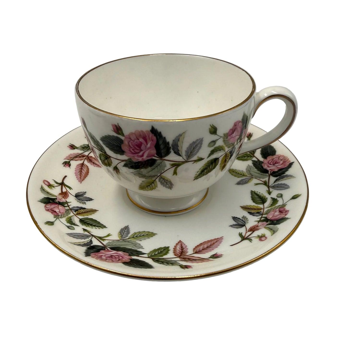 A vintage white porcelain teacup and saucer set decorated with a pink rose and green leaf floral pattern, accented with gold trim.