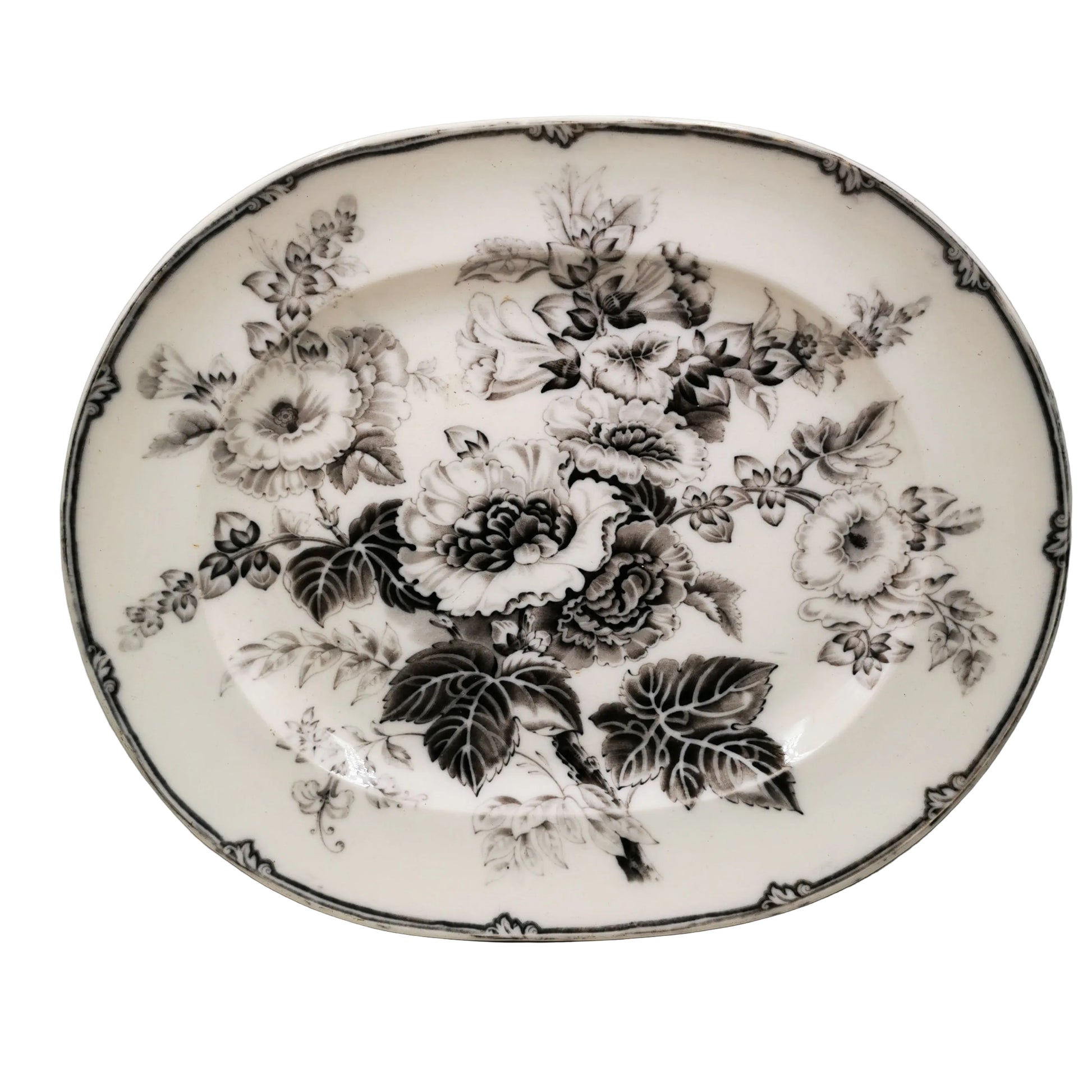 An oval white ceramic serving platter decorated with a black floral pattern of roses and leaves, featuring a decorative black border.