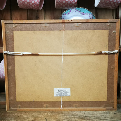 Back of a framed picture with a visible brand label on a wooden surface.