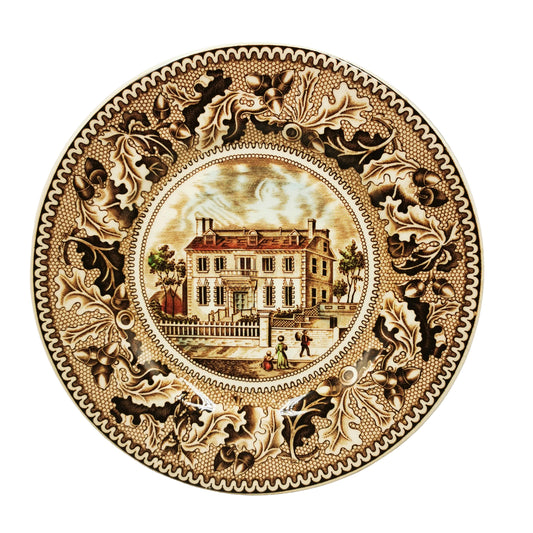 Decorative plate with a house illustration and intricate border on a white background